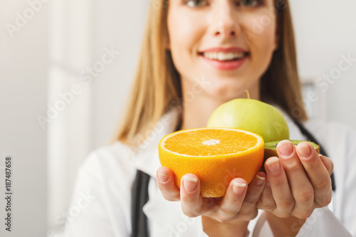 Smiling nutritionist woman with fruit at office