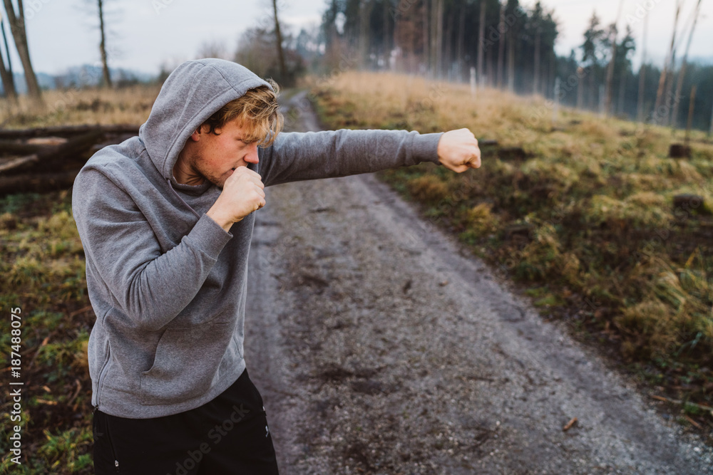 Young man shadow boxing in Austria in a forrest at sunrise Young man shadow boxing in Austria in a forrest at sunrise