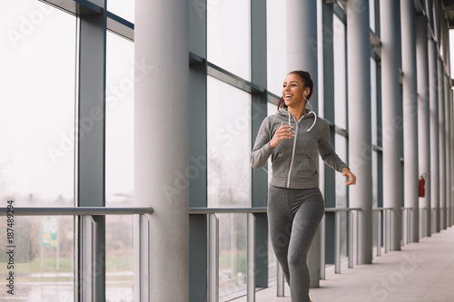 Fit sporty girl running indoors on rainy day.