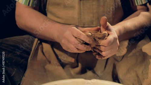 Strong potters hands knead a piece of clay. 