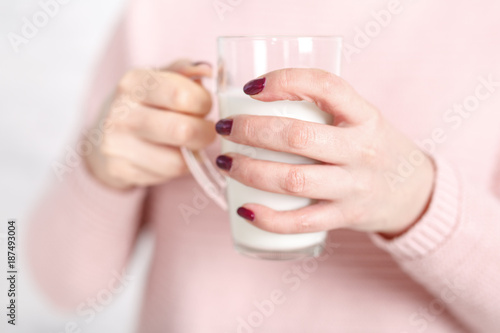 the woman is holding a glass mug of milk