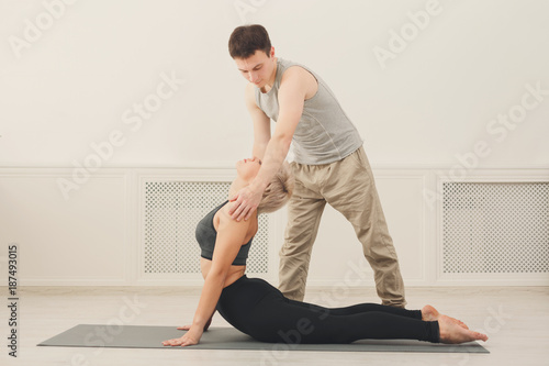 Young woman with yoga instructor in fitness club