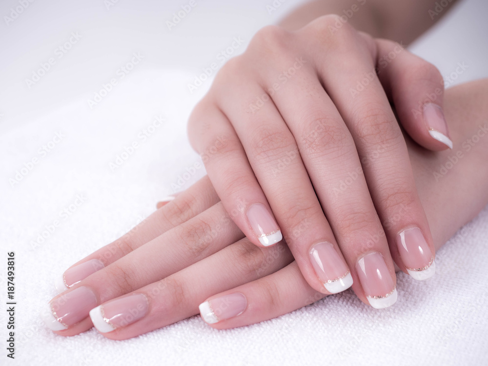 Naklejka premium Close up of beautiful Woman Hands. Spa and Manicure concept. Female hands with french manicure. Soft skin, skincare concept. Beauty nails. over beige background