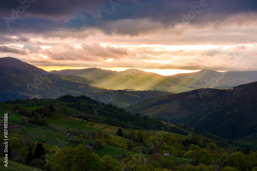gorgeous mountainous countryside at sunset. beams of light break through heavy clouds. rolling hills with rural fields in the shade. spectacular springtime landscape © Pellinni