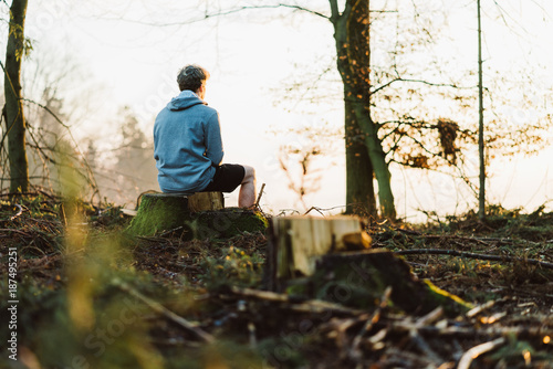 Young man meditating at sunrise in a forrest in Austria
