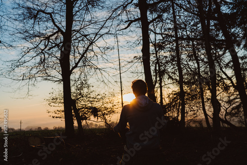 Young man meditating at sunrise in a forrest in Austria