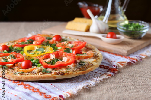 Cooked pizza, vegetables and ingredients are on the table.