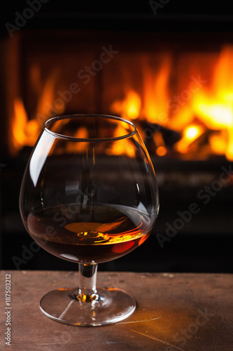 a glass of cognac in front of fireplace