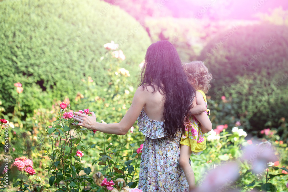 Woman hold child girl at blossoming roses on idyllic day Woman hold child girl at blossoming roses on idyllic day