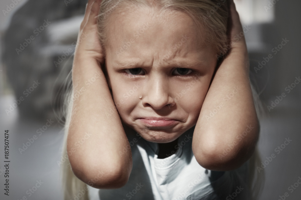 Helpless little girl covering her ears indoors. Child abuse concept Helpless little girl covering her ears indoors. Child abuse concept