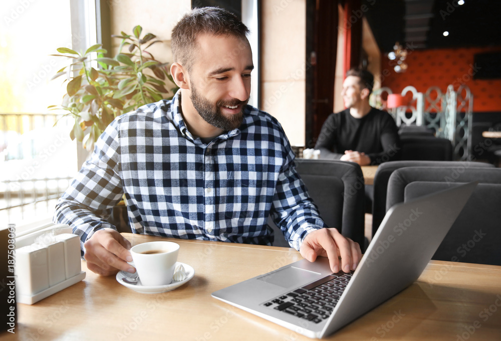 Young hipster man with coffee and laptop in cafe Young hipster man with coffee and laptop in cafe