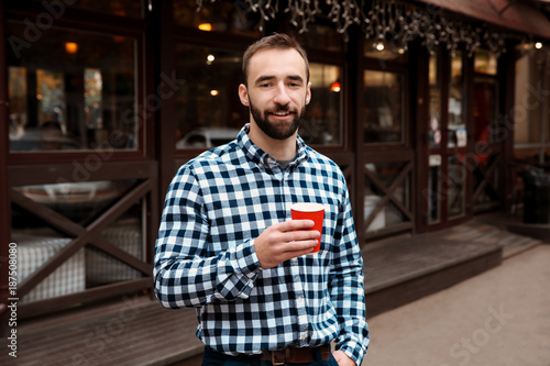 Young hipster man with cup of coffee outdoors