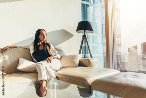 Canvas Print Portrait of successful businesswoman wearing elegant formal suit sitting on leat