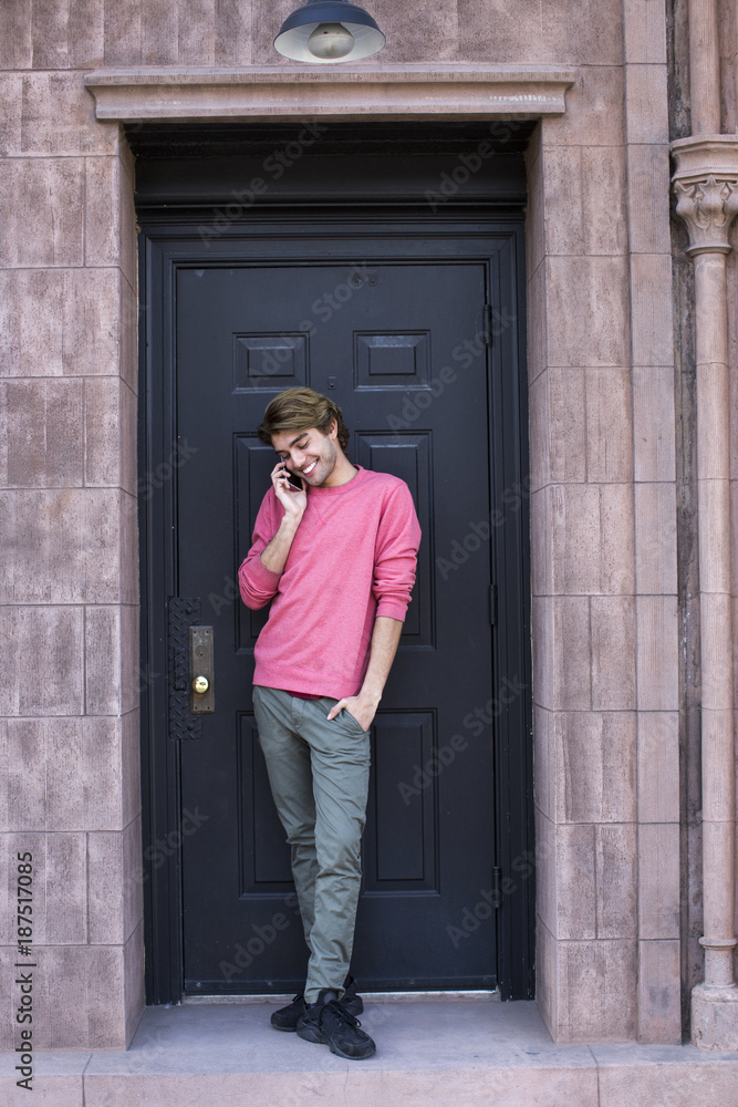 A young man in pink sweater using a cellphone. A young man in pink sweater using a cellphone.