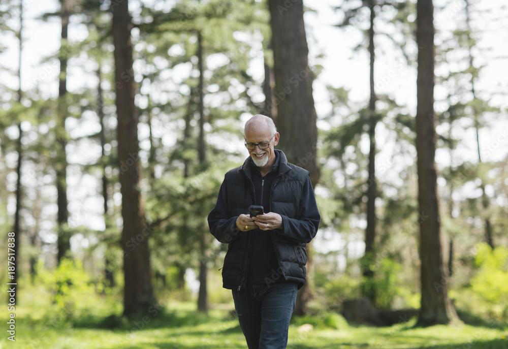 Mature man smiling while looking at mobile phone outside Mature man smiling while looking at mobile phone outside