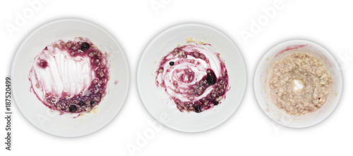 A set of white plates with porridge and blueberry jam leftovers isolated on white background. Messthetics aesthetic concept. A photo from above.