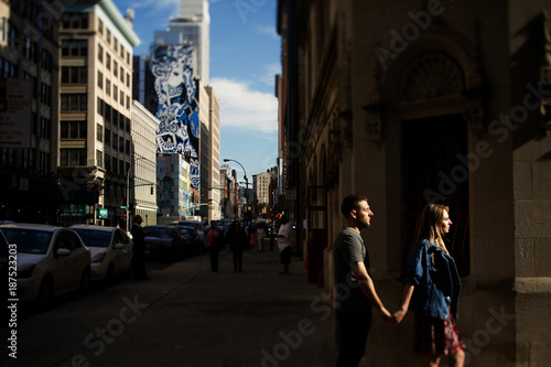 Man and woman hold each other hands tender walking across the street in the morning New York photo