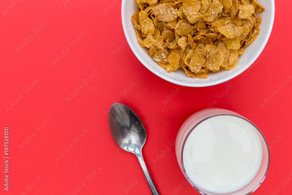 Cornflakes breakfast cereal bowl with milk and spoon on red background foto  de Stock | Adobe Stock