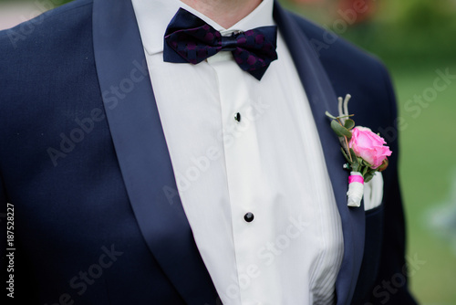 Portrait of handsome stylish groom with pink boutonniere
