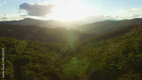 Slow rise over mountains and forest at sunset with sun flare photo