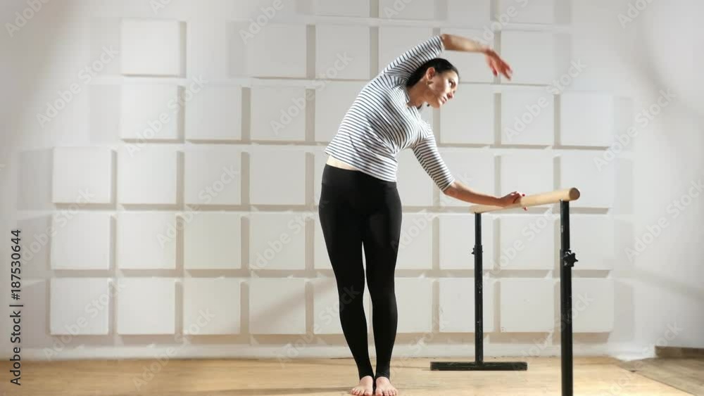 An exciting view of a sportive woman who stands at a crossbar and keeps it. At the same time she bends aside and raises her hand up to train her body An exciting view of a sportive woman who stands at a crossbar and keeps it. At the same time she bends aside and raises her hand up to train her body
