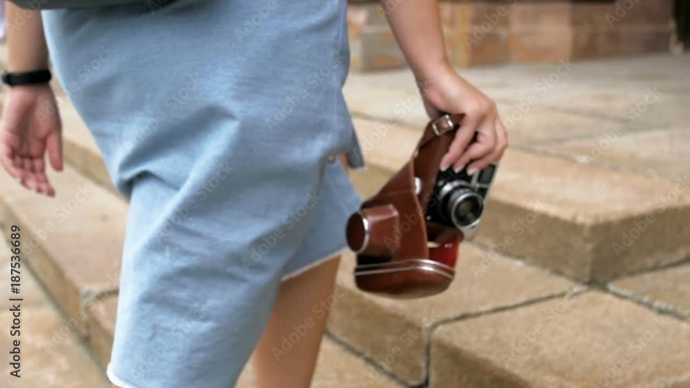 Slow motion closeup video of young woman walking with vintage film camera Slow motion closeup video of young woman walking with vintage film camera