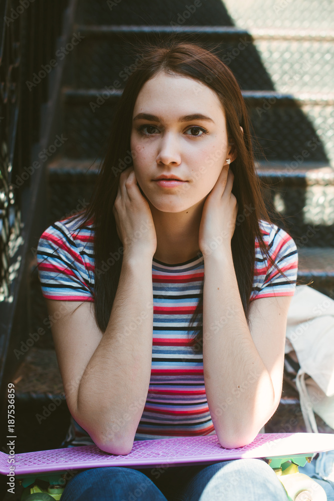 Sporty and feminine young woman on stoop with skateboard Sporty and feminine young woman on stoop with skateboard