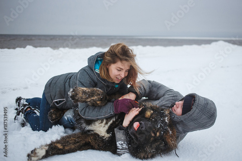 Girl and man is playing with dog in snow, Happy holidays, love moments and rest in nature in winter