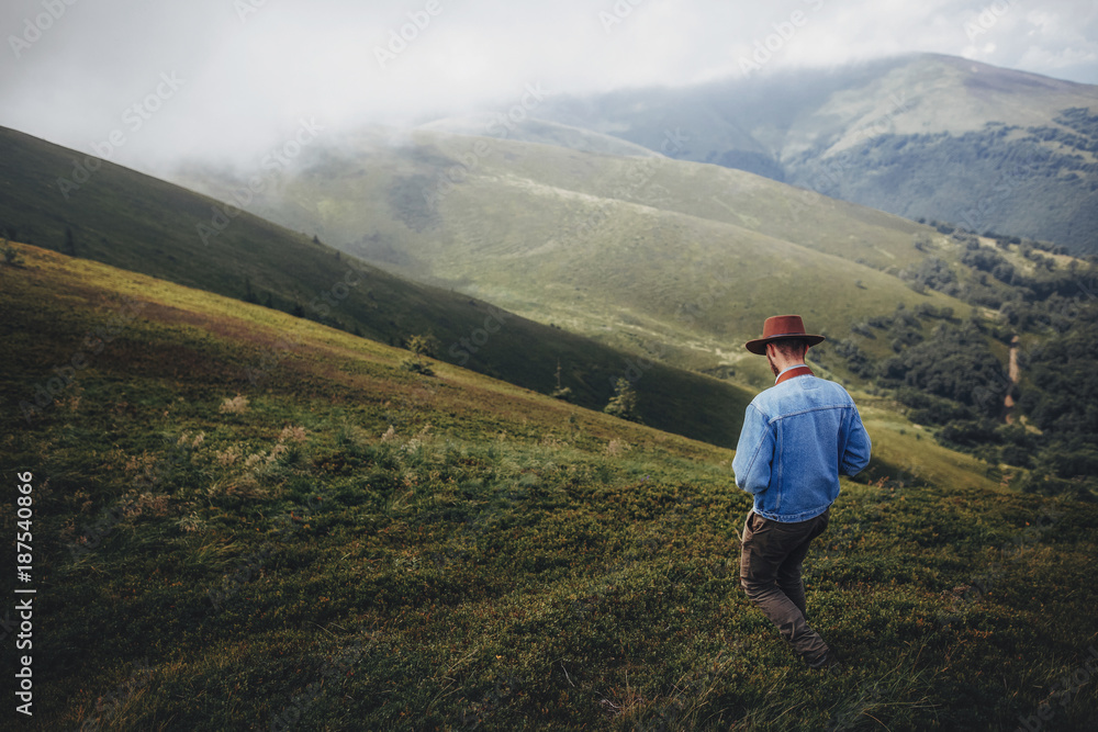wanderlust and travel concept. man traveler in hat with photo camera walking on top of misty mountain. stylish hipster exploring outdoors. space for text. atmospheric moment wanderlust and travel concept. man traveler in hat with photo camera walking on top of misty mountain. stylish hipster exploring outdoors. space for text. atmospheric moment