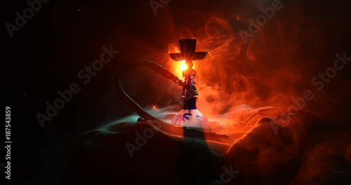 Hookah hot coals on shisha bowl on orange (like fire) clouds of steam on dark background. Stylish oriental shisha. Shisha Concept. On rotating display.  photo