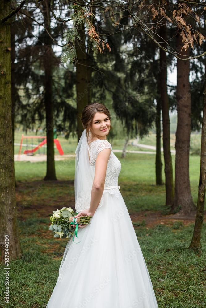 Handsome gorgeous bride in white wedding dress with bridal bouquet