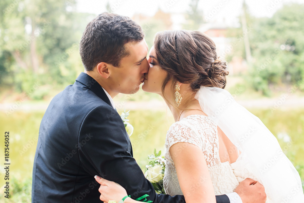 Beautifull wedding couple kissing and embracing outdoor. One beautiful wedding day Beautifull wedding couple kissing and embracing outdoor. One beautiful wedding day