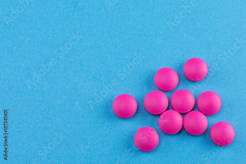 pink pills on blue background with copy space