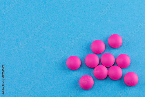 Fotografie pink pills on blue background with copy space