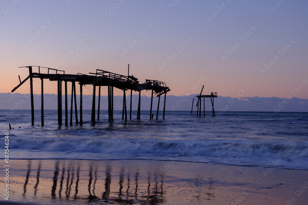 Storm battered broken down pier at sunrise on the Atlantic ocean off the North Carolina Coast on the Outer Banks Cape Hatteras