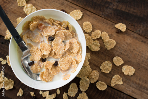 breakfast cereal ( cornflakes ) with milk in a bowl on a wooden table background. healthy eating concept