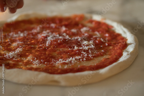 tomato based pizza being topped with cheese