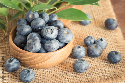 Blueberry in a wooden bowl on a sack.