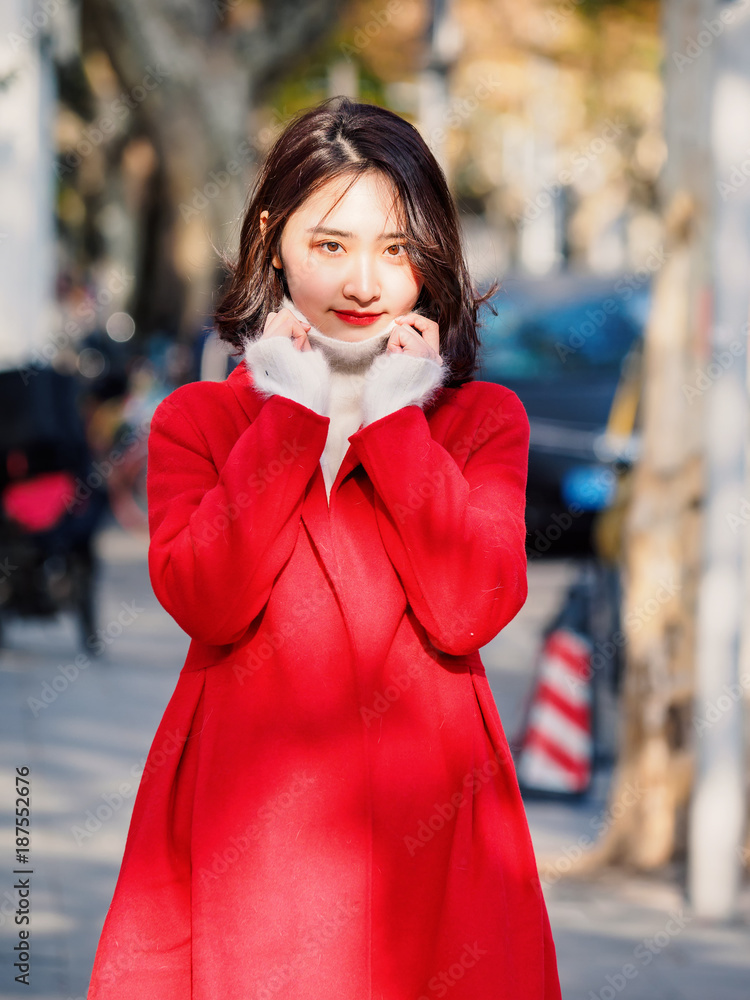 Beautiful young brunette woman wearing a red coat in autumn city. Outdoor fashion portrait of glamour young Chinese cheerful stylish lady in street. Emotions, people, beauty and lifestyle concept. Beautiful young brunette woman wearing a red coat in autumn city. Outdoor fashion portrait of glamour young Chinese cheerful stylish lady in street. Emotions, people, beauty and lifestyle concept.