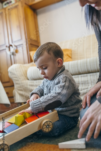 Toddler boy playing with a wooden game building in the living room