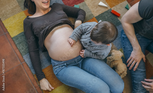 Photography Little boy tickling the belly of his pregnant mother with his father watching