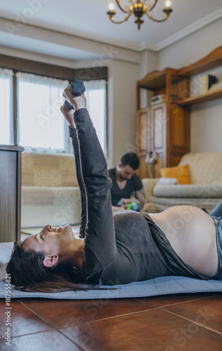 Pregnant woman exercising in the living room of her house