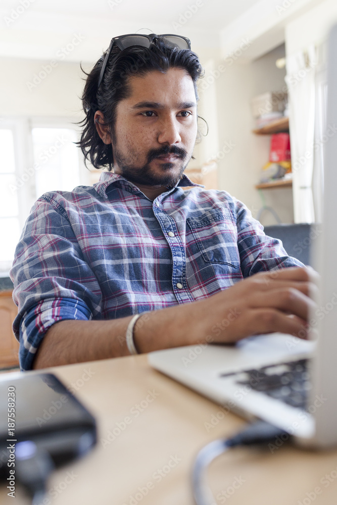Young south asian man working on a laptop. Young south asian man working on a laptop.