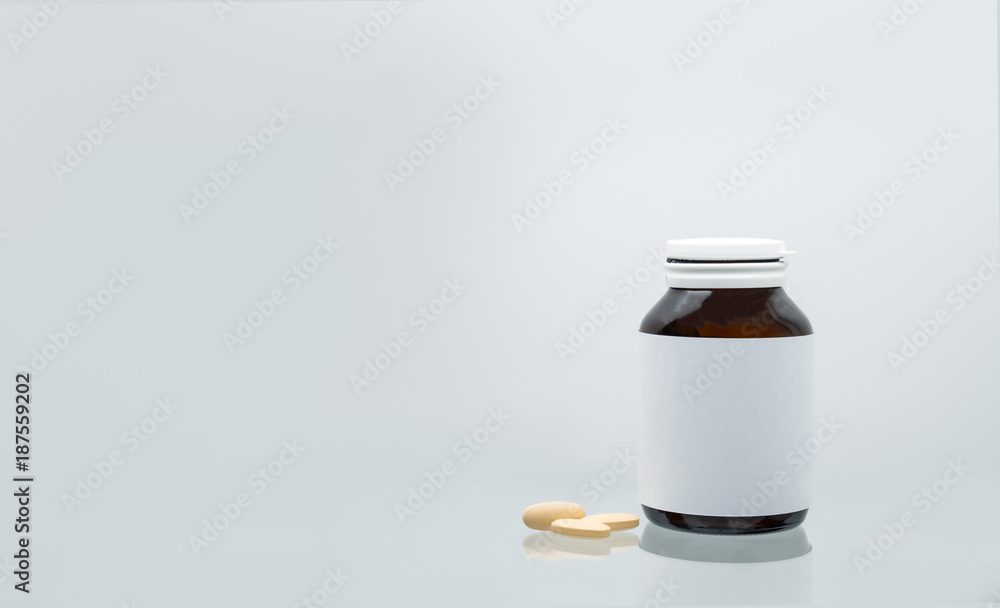 Three tablets of vitamin C 1,000 mg on white background and amber bottle with blank label and copy space for text. Vitamin and supplement concept. Antioxidant Three tablets of vitamin C 1,000 mg on white background and amber bottle with blank label and copy space for text. Vitamin and supplement concept. Antioxidant