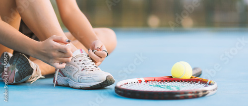 Tennis player tying shoelaces in court