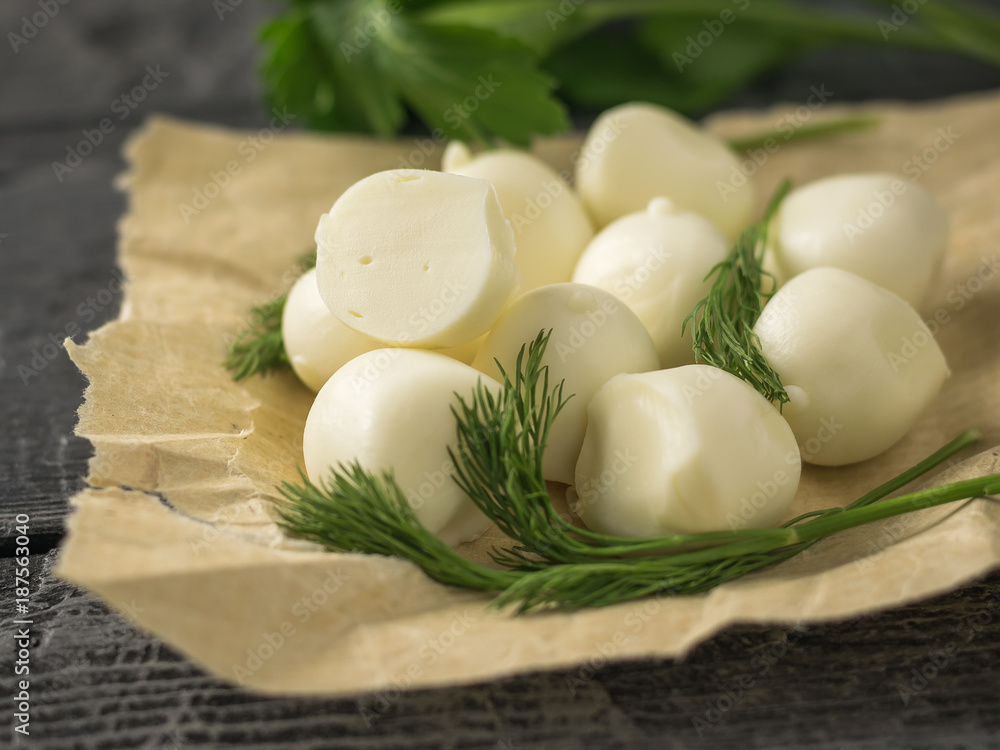 Freshly made balls of mozzarella cheese in the wrapping paper on a rustic table. Freshly made balls of mozzarella cheese in the wrapping paper on a rustic table.