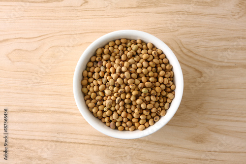 Soybeans in a white bowl on a wooden floor.