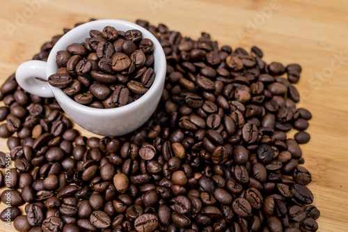 White coffee cup with roast coffee beans on a brown coffee grains background