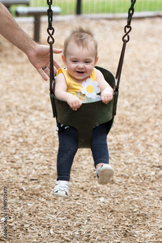 Happy beautiful baby enjoying outdoor activities and smiling while swinging