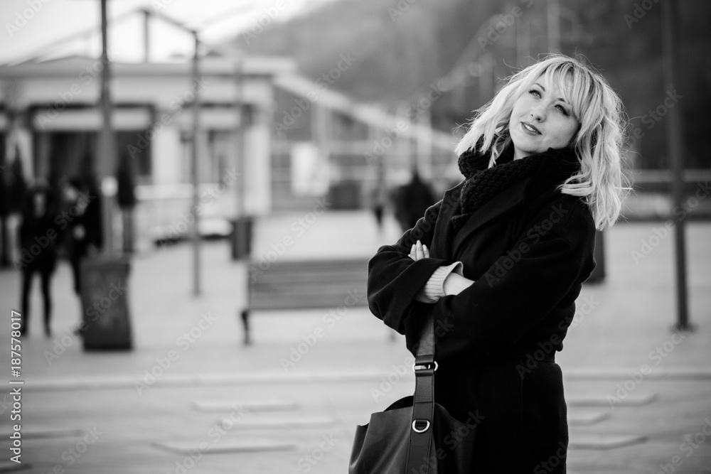 Beautiful nice middle age business woman with blond hair at evening walk at the city with romantic mood. Lady wearing in dark coat and scarf. Young woman walking on a city street Beautiful nice middle age business woman with blond hair at evening walk at the city with romantic mood. Lady wearing in dark coat and scarf. Young woman walking on a city street